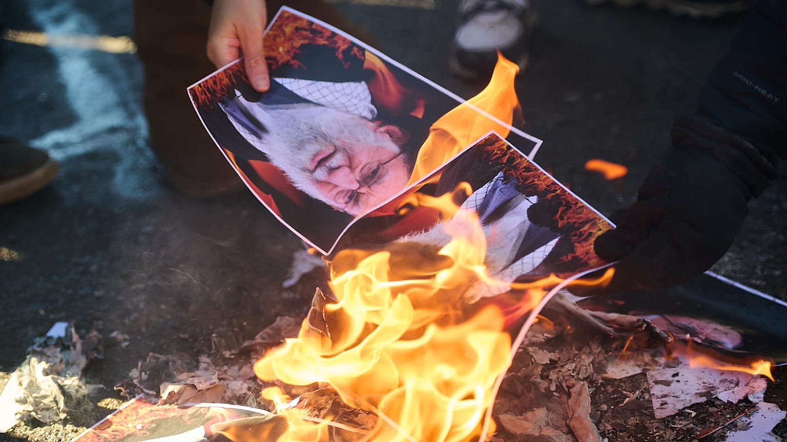 Protesters burn pictures of Iranian Ayatollah Ali Khamenei as they march in support of regime change in Iran during a protest in Toronto, 1 February 2026
