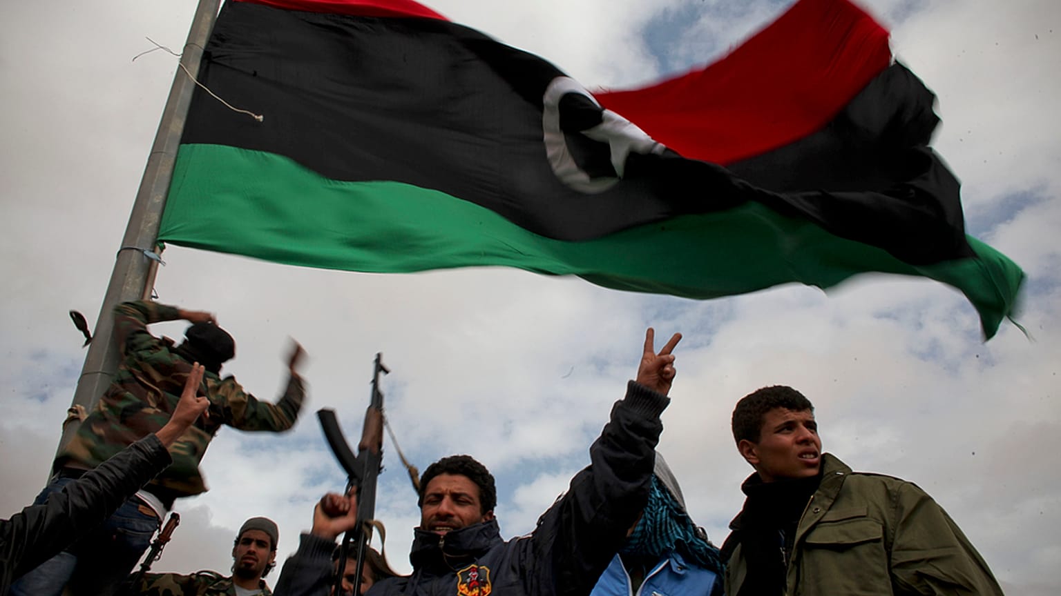 Libyan volunteers wave a pre-Qaddafi flag on the outskirts of the eastern Libyan city of Ras Lanuf, Tuesday, 8 March 2011.