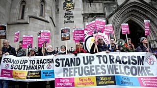 Stand Up To Racism campaigners hold banners outside the High Court in London, 19 December, 2022