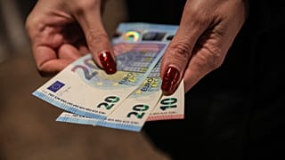 A person poses with euro banknotes withdrawn from an ATM in Sofia, Thursday, Jan. 1, 2026, as the country joins the euro currency union.