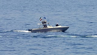 FILE: An Iranian Revolutionary Guard vessel watches an American warship in the Strait of Hormuz, May 19, 2023.