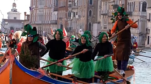 Colourful boats with crews dressed in fancy costumes row along Venice's Grand Canal 